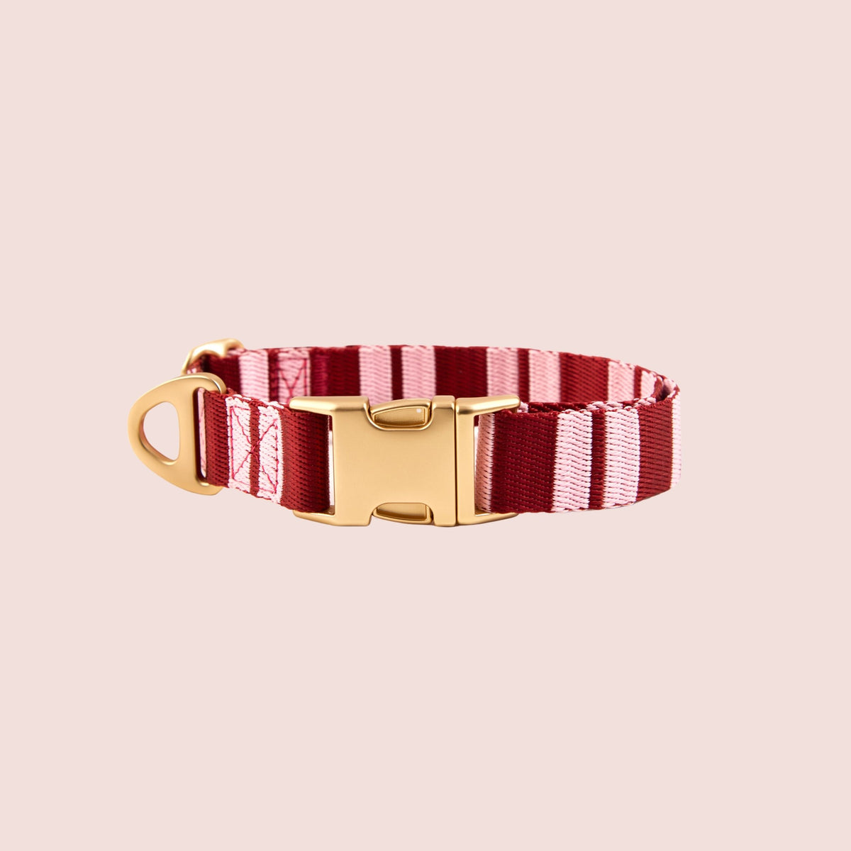 The Hersh Bed Striped designer dog collar in pink and burgundy with gold hardware on a pink background.